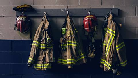 Firefighter uniforms hanging on a coat rack.