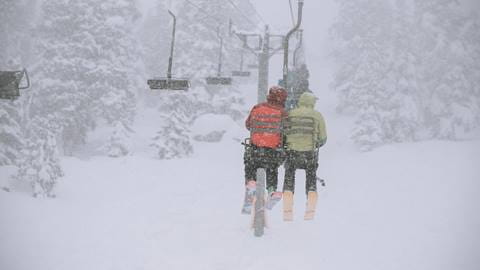 two friends on a chairlift in a storm