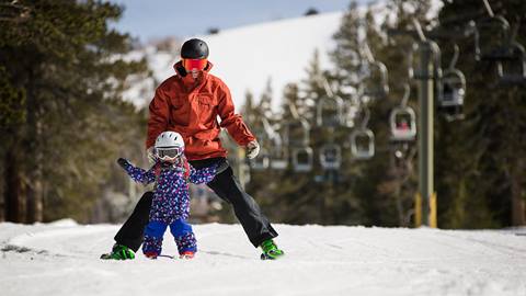 dad helping toddler ski 